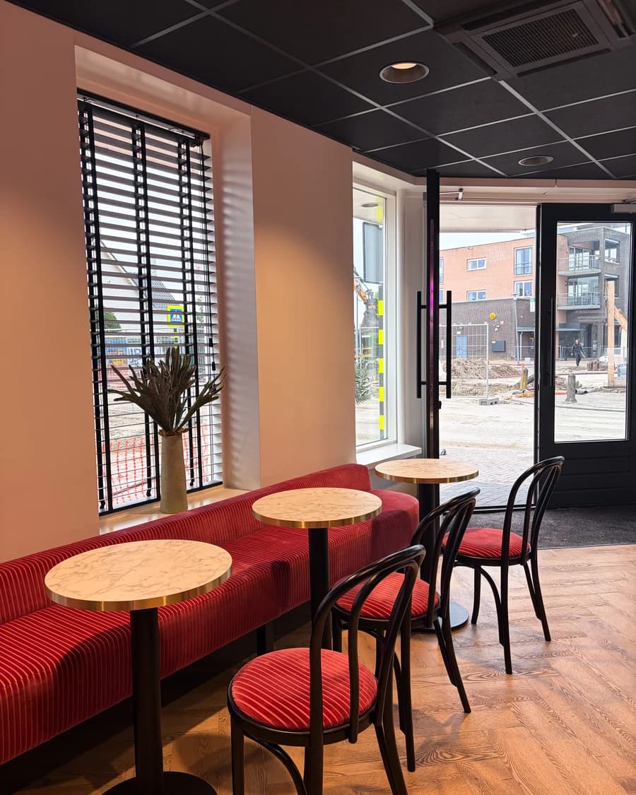 Tafeltjes en de rode bank bij het raam in de salon
